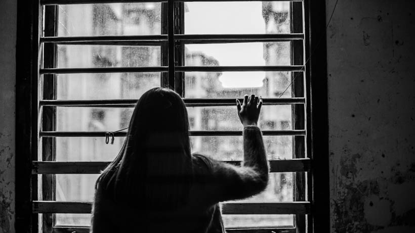 Νεαρή γυναίκα στενοχωρημένη μετά από κάποιον χωρισμό κοιτάει έξω από το παράθυρο