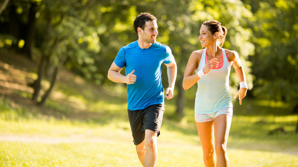 Άντρας και γυναίκα απολαμβάνουν τα οφέλη της αερόβιας άσκησης. Τρέχουν μαζί στην ύπαιθρο.