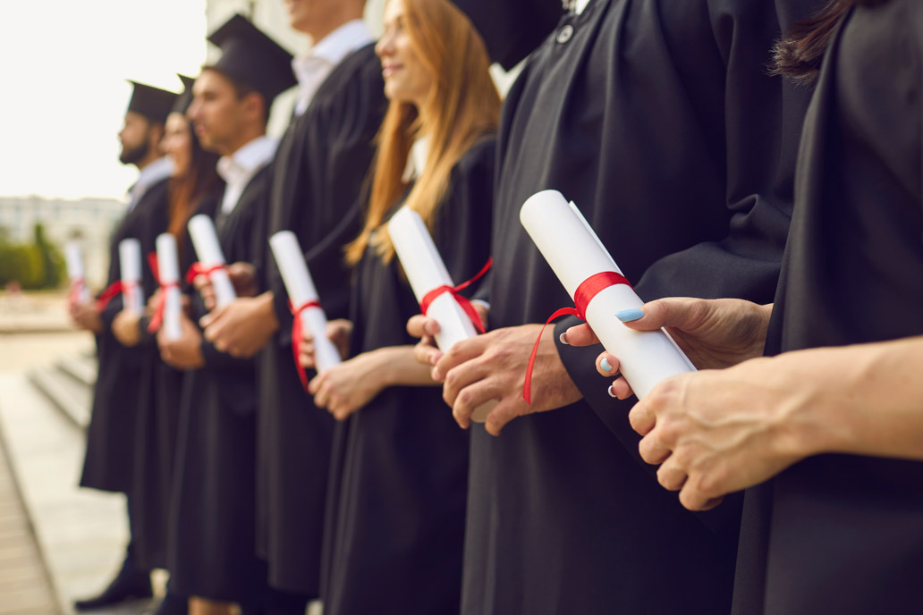 Φοιτητές με διπλώματα στα χέρια στέκονται στη σειρά κατά τη διάρκεια αποφοίτησής τους και απονομής του διδακτορικού τους.