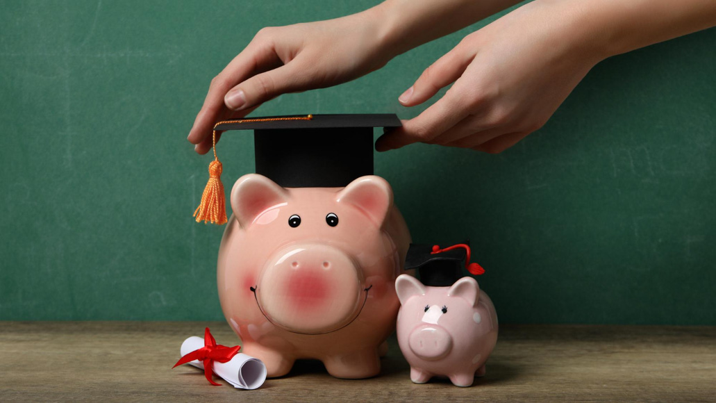 Θεματική εικόνα για το πώς να βγάλεις λεφτά ως φοιτητής. Κουμπαράς σε σχήμα γουρουνιού με ένα καπέλο αποφοίτησης από πάνω.