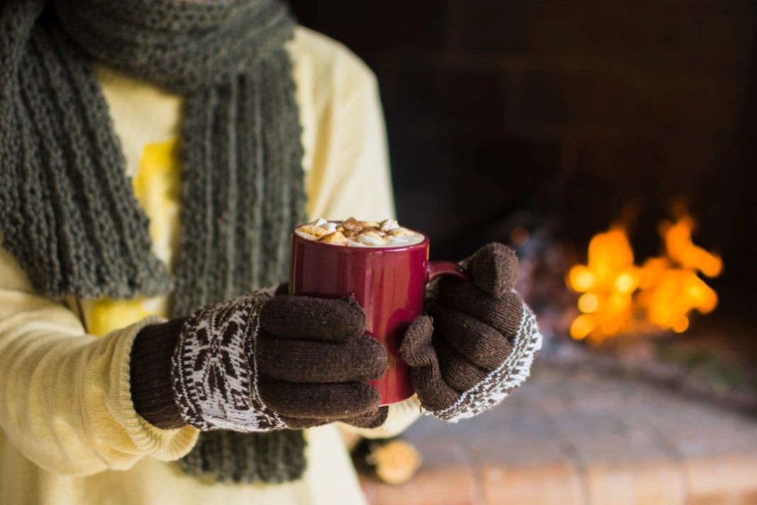 Άτομο με γάντια κρατά ένα από τα καλύτερα ζεστά ροφήματα για χειμώνα: μια κούπα με σοκολάτα.