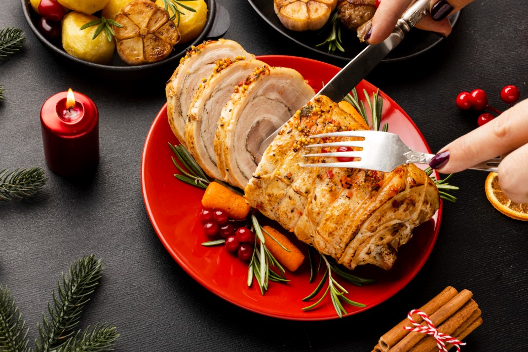 Ιδέα για φαγητά για χριστουγεννιάτικο τραπέζι. Γυναίκα κόβει με μαχαίρι γεμιστό χοιρινό.