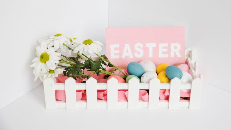 Καφάσι με πολύχρωμα πασχαλινά αυγά, λουλούδια και κάρτα για καλό Πάσχα